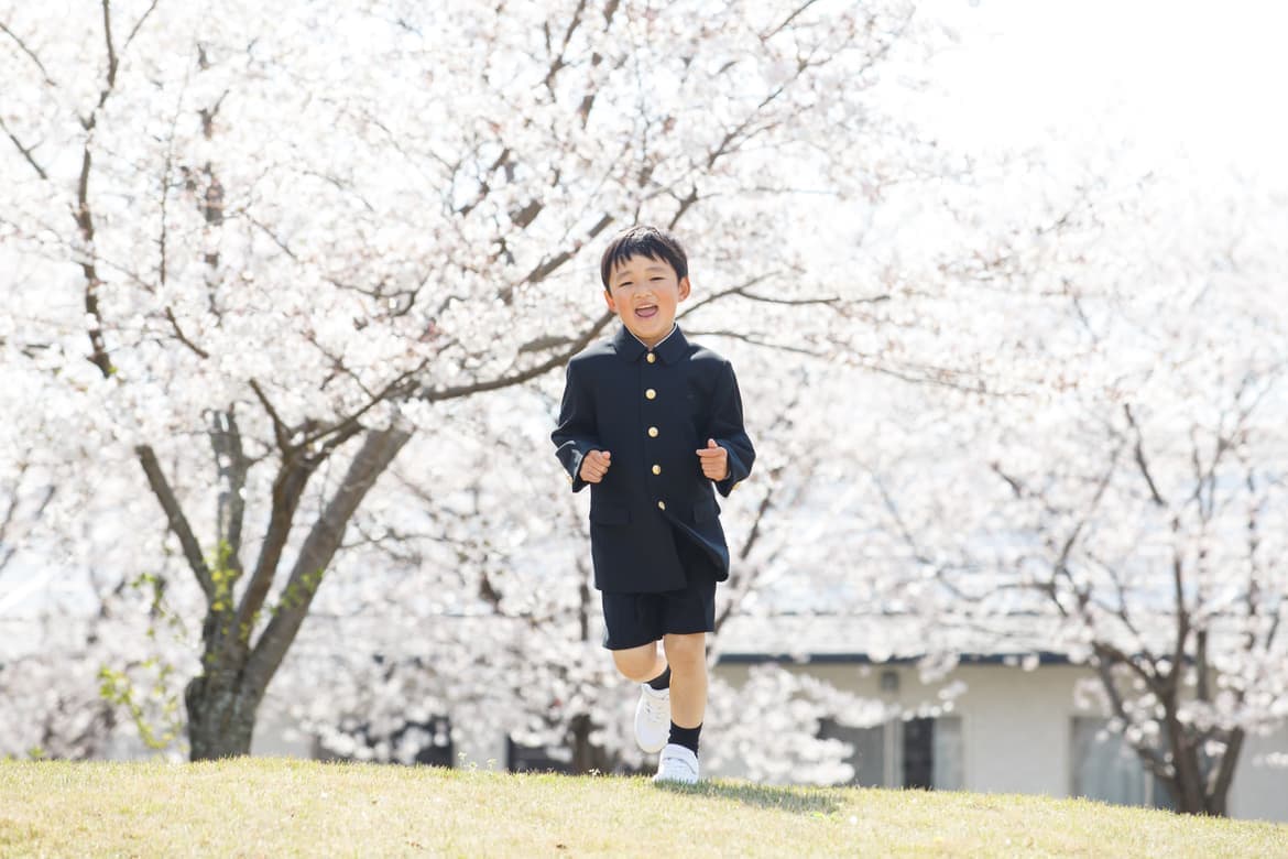 桜の前で制服で走る男の子