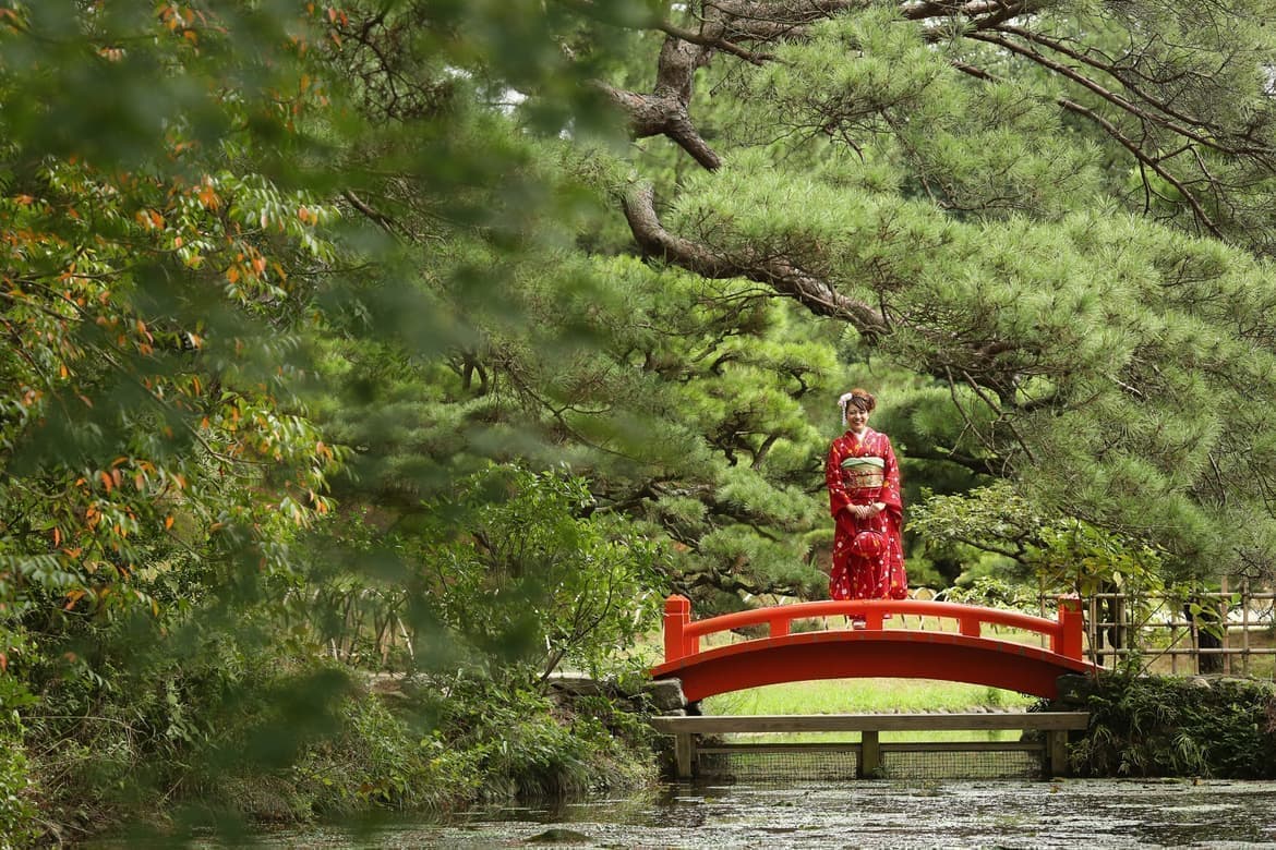 赤い橋に立っている振袖の女の子