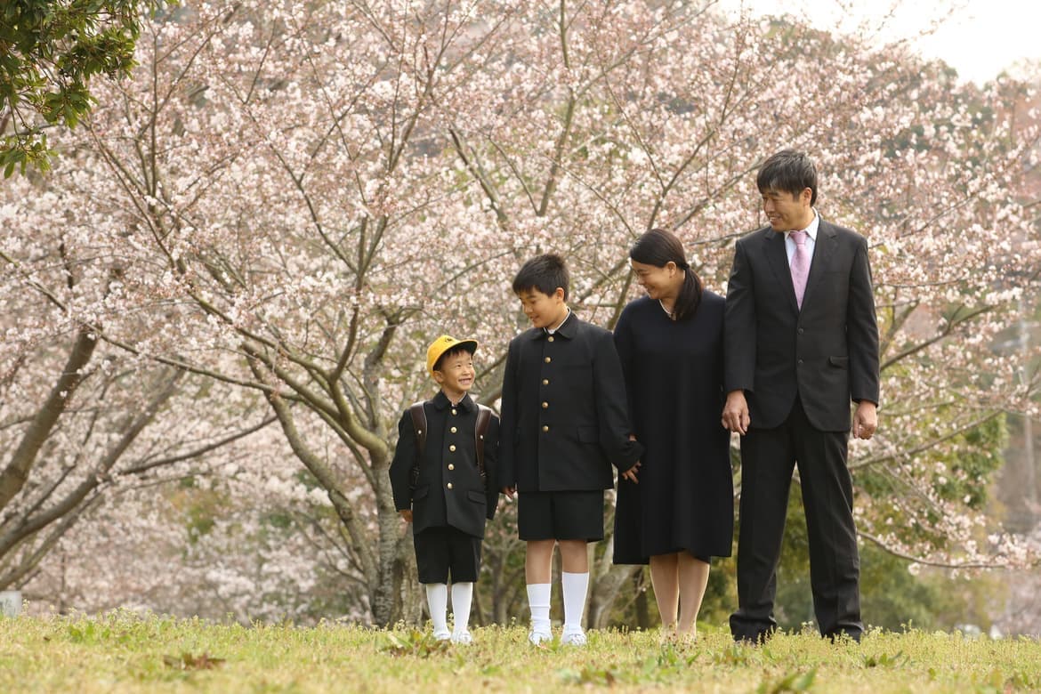 桜の前で入学写真を撮る家族